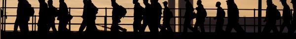 Silhouette of industrial workers crossing a bridge in front of a smoke stack