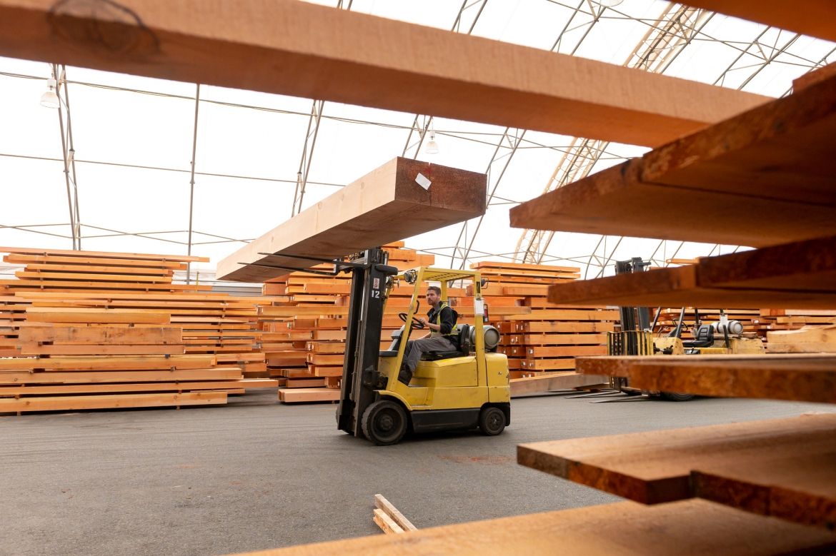 A worker drives a forklift in a lumber mill