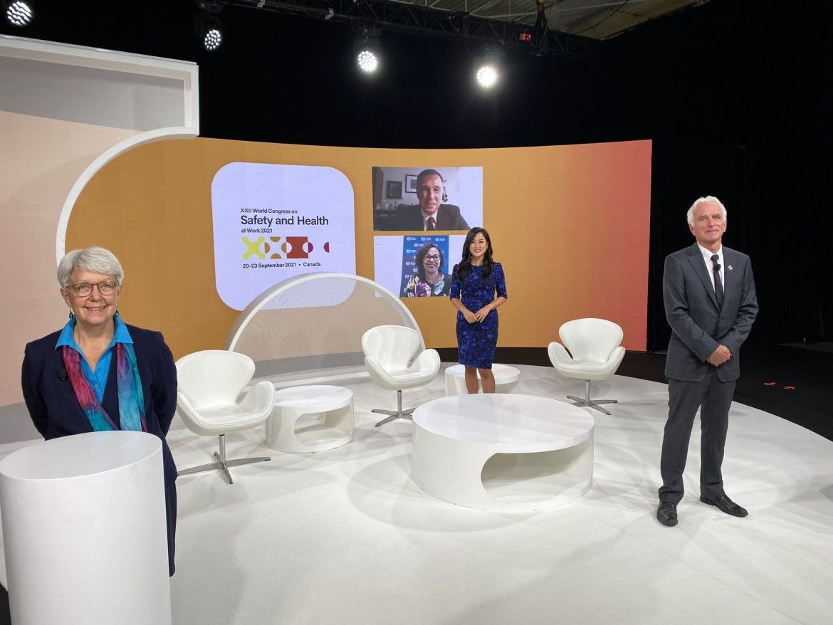 World Congress hosts stand in a studio, with presenters appearing on TV screens in the background