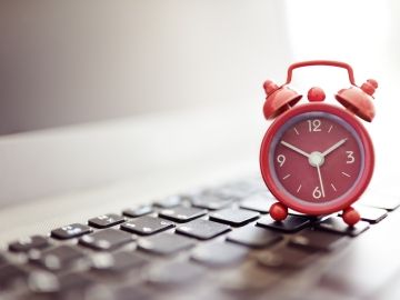 An alarm clock sits on a computer keyboard.