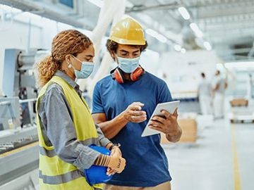 Two masked workers discuss about a document