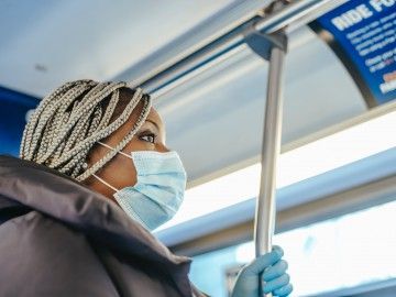 A masked worker riding a bus