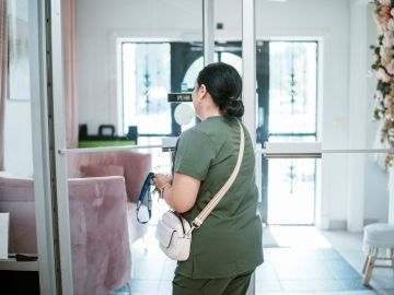 A woman walks into the front door of her business.