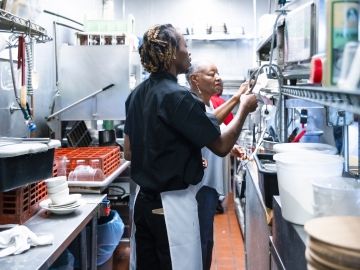 Two workers in a restaurant kitchen.