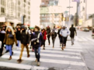 A blurry image of a busy sidewalk crossing