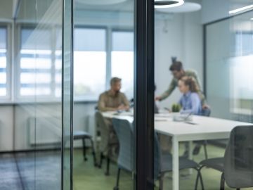 Business professionals in casual wear, sit around a table in a boardroom, with blurred background