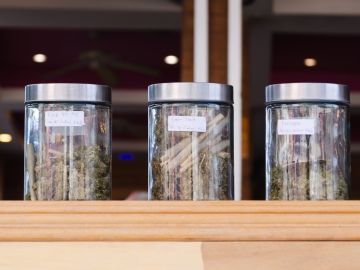Jars of cannabis on a store display, as seen from outside