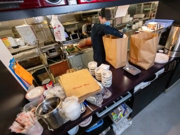 Masked restaurant worker prepares take-out food orders