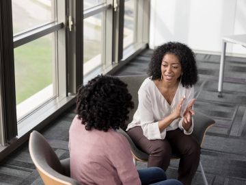 Two women sharing a confidence at work