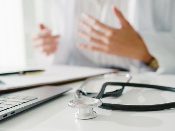 An out-of-frame doctor talks to someone on a laptop screen