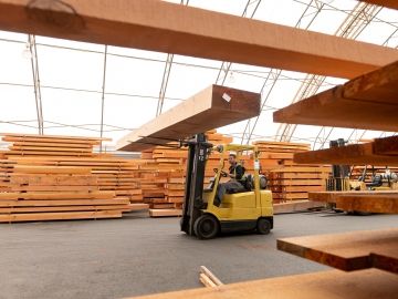 A worker drives a forklift in a lumber mill