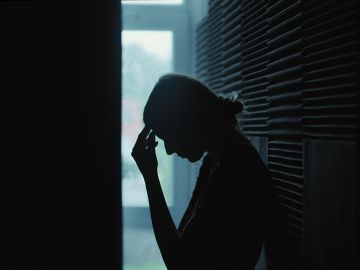 A silhouette of a women holding her head in her hand