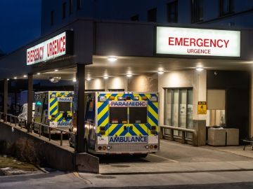 Two ambulance parked at the emergency entrance of a hospital in the night