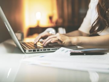 A female worker at a laptop in her home, with a night lamp in the background indicating the evening hours