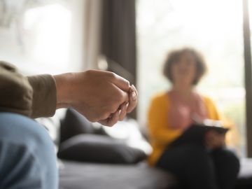 A person's hands clasped in a therapist appointment.