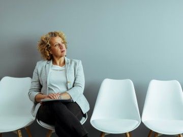 An older female worker ponders decision while sitting in waiting room