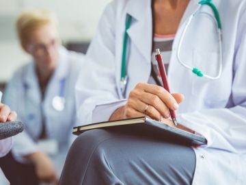 A group of physician's sitting in a room, prepared to take notes.