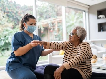 A homecare worker supporting her patient with her arm exercises