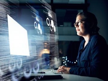 A woman studies data and charts projected on a screen