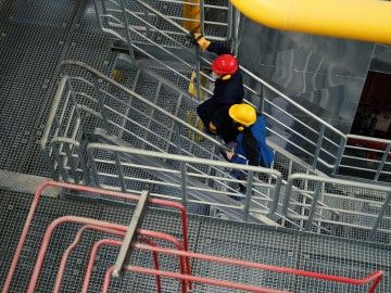 Overhead view of two people in safety helmets walking up the stairs in a plant