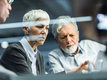 Two grey-haired workers have a discussion