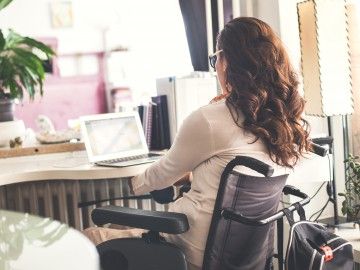 A woman in a wheelchair works from her home office