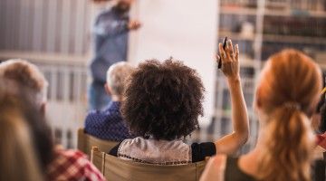 Rear view of a woman raising hand at training seminar