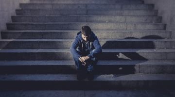 A man sits on a dimly lit staircase.