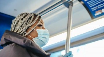 A masked worker riding a bus