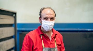 A worker wearing an apron and a cloth facial mask