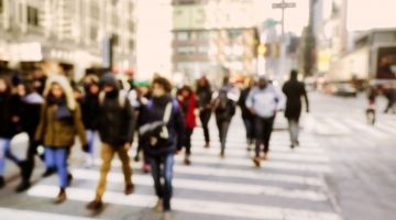 A blurry image of a busy sidewalk crossing