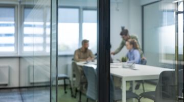 Business professionals in casual wear, sit around a table in a boardroom, with blurred background