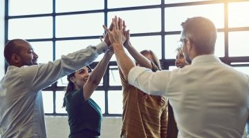 A group of office workers high-fiving each other