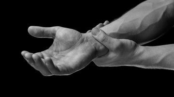 A close-up black and white photo showing hand and wrist in pain