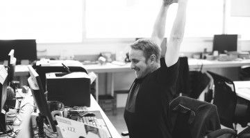 Man stretches at computer work station