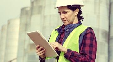 A young female engineer on a construction site is reviewing a document
