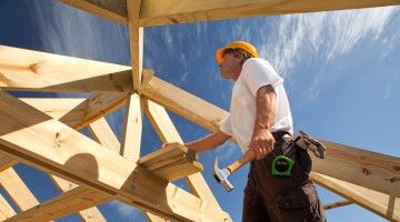 Worker with hammer works on roof frame