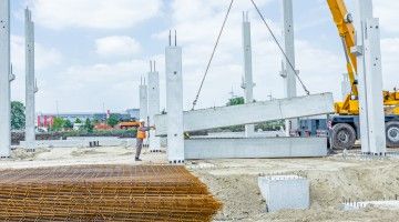 A worker guides a crane lifting concrete at a construction site