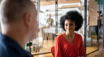 A woman smiles sympathetically at a colleague in an office