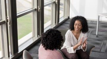 Two women sharing a confidence at work