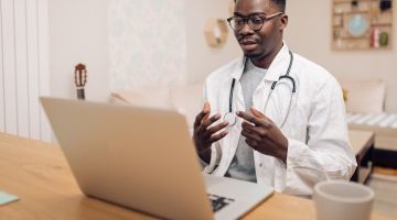 A young male doctor engaging in an online discussion using his laptop