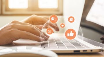 A close-up of a pair of hands typing at a laptop, with email and social media symbols superimposed