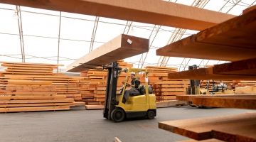 A worker drives a forklift in a lumber mill