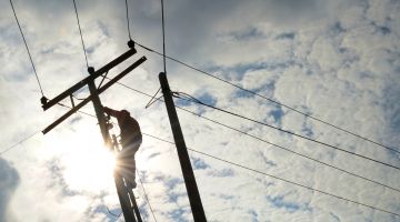 View from the ground of utility technician working on hydro lines