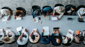 An overhead shot of a boardroom table full of people