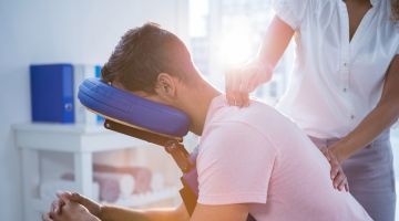 A physiotherapist is treating a man with neck and back pain