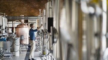 A brewery worker inspects equipment