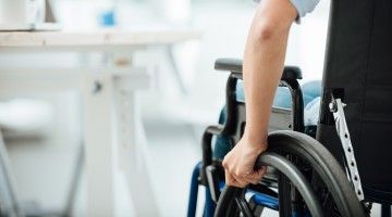 Close-up of man in wheelchair approaching desk