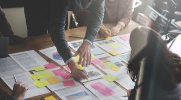 Co-workers strategize at table with sticky notes