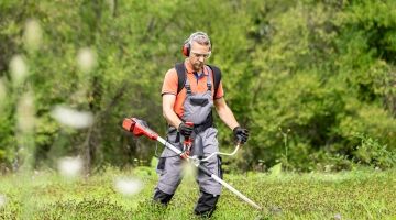 A landscape worker cutting grass.